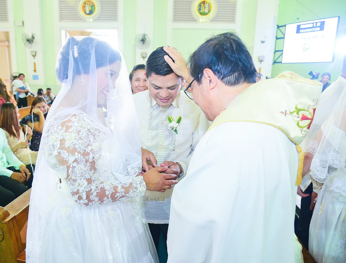 A sacred moment as Reverend Father Rey Reyes, the officiating priest (right), blesses Carl Jason (center) and Donna Jean (left) De Luna.